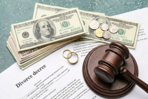 4a264e83-7e93-4231-b747-35f25d3c6618 - Dixon Law Firm Divorce decree document with a gavel, stacks of hundred-dollar bills, coins, and wedding bands on a table.